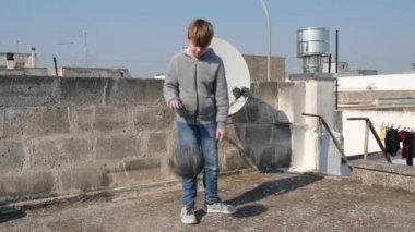 Coronavirus covid-19 karantinası sırasında bir çocuk evinin çatısına top sürüyor. Sağlıklı kalmak için çocuk sepeti. Çocukların evde antrenman yapması, karantina sporu