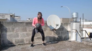 Ev soyutlanmış. Genç kız karantina sırasında evinin çatısında spor yapıyor. Spor giyim sektöründe kadın fitness eğitimi. Spor ve sağlık anlayışı. Evde karantina sporu