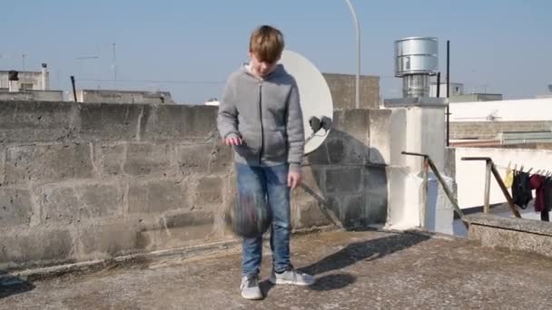 Хлопчик дриблінг м'яча на даху свого будинку під час карантину коронавірусу ковід-19. Дитячий кошик, щоб залишатися здоровим. Ідея діяльності дітей домашніх тренувань, карантинного спорту — стокове відео