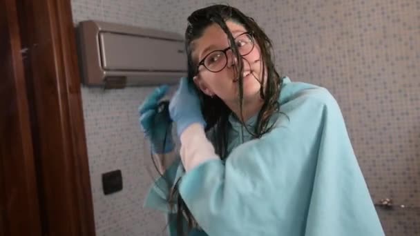Миллениальная девушка красит свои светлые волосы в синий цвет дома в ванной комнате. Уход за волосами на дому во время карантина коронавируса . — стоковое видео