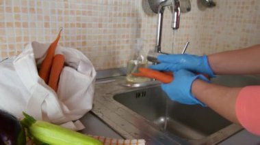 Tıbbi eldiven takan kadın eli kapalı Coronavirus salgını sırasında havuç yıkıyor. Kendini Cvid-19 'dan korumak için. Karantina karantinasında kendini tecrit