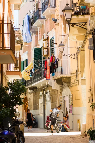 BARI, ITALY - 11 Temmuz 2018, İtalyan şehri Bari 'nin dar bir caddesinin manzarası, sokakta keten kuruyor, çocuklar bisikletle konuşuyor.