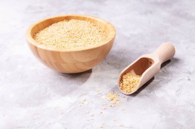 Pişmemiş çiğ bulguru taneleri bir kasede ve tahta bir kaşıkta. Sağlıklı, besleyici, vejetaryen, diyet ürünü. Buğday tanelerinden yapılan organik ürün