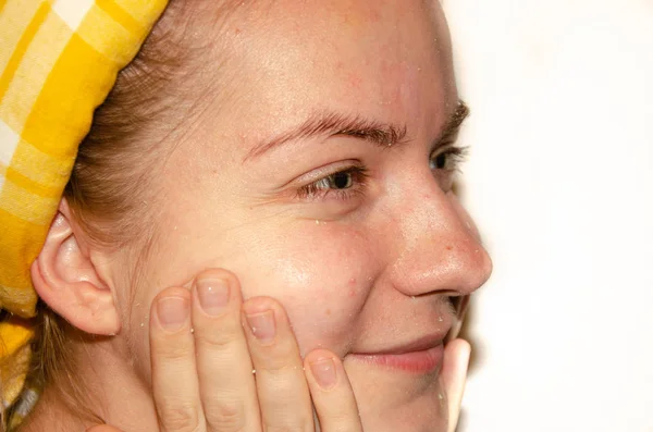 A European girl is applying Korean cosmetics to her face mask. Cleanses pores, grease, acne, wrinkles. Close-up face of a girl with skin problems. Mousse, spray, face scrub and face wash.Yellow Sponge