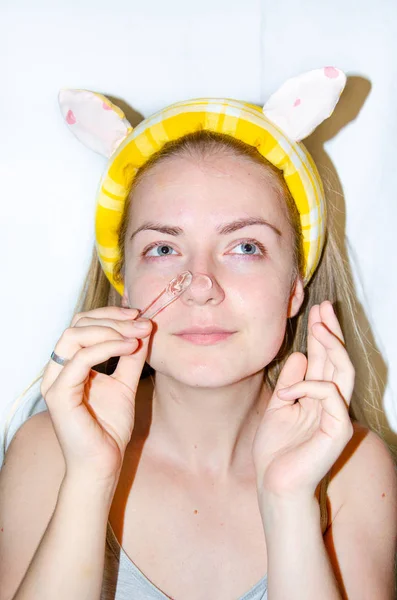 A European girl is applying Korean cosmetics to her face mask. Cleanses pores, grease, acne, wrinkles. Close-up face of a girl with skin problems. Mousse, spray, face scrub and face wash.Yellow Sponge