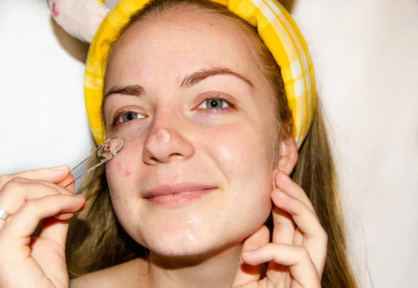 A European girl is applying Korean cosmetics to her face mask. Cleanses pores, grease, acne, wrinkles. Close-up face of a girl with skin problems. Mousse, spray, face scrub and face wash.Yellow Sponge