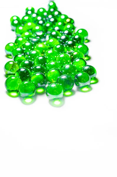 Zelené skleněné koule. Skleněná kulička na bílém pozadí. Makro z různých úhlů a ve formě srdce. — Stock fotografie