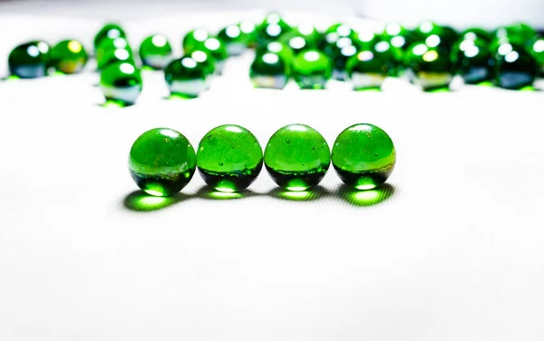 Grüne Glaskugeln. Glaskugel auf weißem Hintergrund. Makro aus verschiedenen Blickwinkeln und in Herzform. — Stockfoto