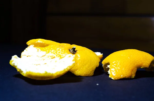 Bright mandarin on a black background. Tangerine skins on a dark background. Mandarin and its skins in macro. Slices, braces of mandarin. Citrus fruits in macro. — Stock Photo, Image