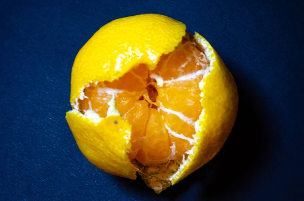 Mandarina brillante sobre fondo negro. Pieles de mandarina sobre un fondo oscuro. Mandarín y sus pieles en macro. Rebanadas, tirantes de mandarina. Cítricos en macro . — Foto de Stock