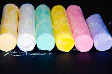 Siyah arka planda çocukların renkli pastel boyaları var. Farklı açılarda ve farklı taraflarda çizdiğin için tebeşir. Makro çizim için çocuk tebeşiri.