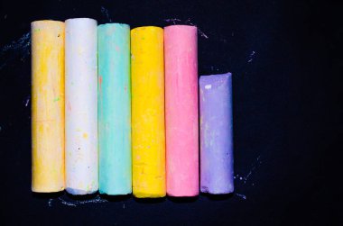 Siyah arka planda çocukların renkli pastel boyaları var. Farklı açılarda ve farklı taraflarda çizdiğin için tebeşir. Makro çizim için çocuk tebeşiri.
