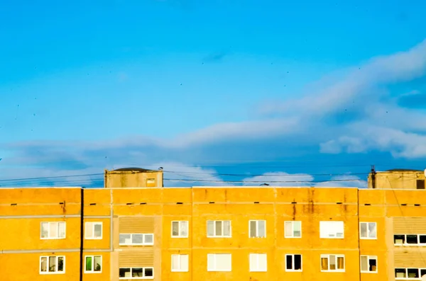 Edifício amarelo brilhante de 9 andares em um fundo de céu azul saturado brilhante . — Fotografia de Stock