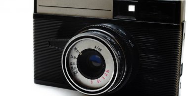 Eski film kamerası. Beyaz arka planda nadir bulunan bir kamera. İlham perilerinin elinde bir kamera. Sovyet fotoğraf ekipmanları. Makro kamera, lens, içerisi, detaylar. 