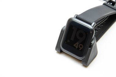 Akıllı bir saat. Beyaz arka planda akıllı bir saat. Akıllı saatler için şarj aleti. Rıhtım istasyonu. Erkeklerin elleri akıllı bir saati tutar ve onları şarj eder. İzle, yakın plan şarj aleti. 