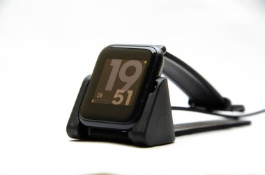 Akıllı bir saat. Beyaz arka planda akıllı bir saat. Akıllı saatler için şarj aleti. Rıhtım istasyonu. Erkeklerin elleri akıllı bir saati tutar ve onları şarj eder. İzle, yakın plan şarj aleti. 