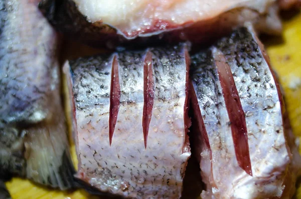 Κομμάτια, τεμαχισμένα ωμά ψάρια σε μια ξύλινη σανίδα. Ψάρια σε μακροεντολή. Ψάρια στο αλάτι. Σκουλήκια στα ψάρια. Κίνδυνος δηλητηρίασης από ψάρια. — Φωτογραφία Αρχείου