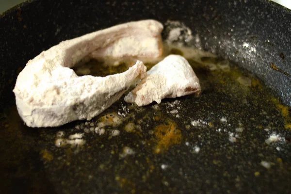 Pescado en masa. Los trozos de pescado en harina se fríen en una sartén con mantequilla. Quemaduras. Peligro Cena de pescado frito . — Foto de Stock