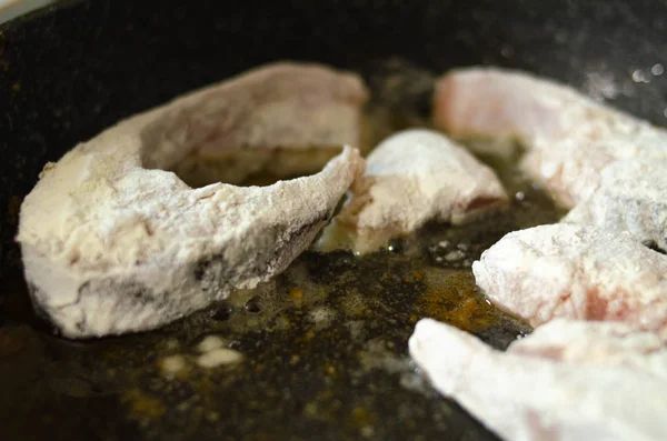 Pescado en masa. Los trozos de pescado en harina se fríen en una sartén con mantequilla. Quemaduras. Peligro Cena de pescado frito . — Foto de Stock