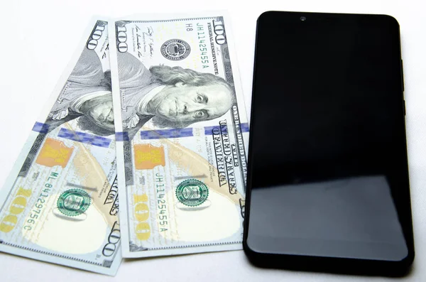 Beyaz arka planda dolar ve akıllı telefon. Akıllı telefonunda dolar var.. 