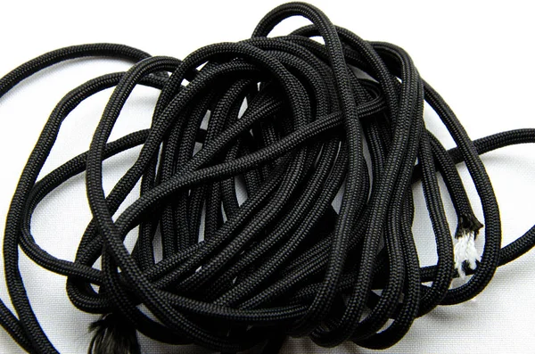 Corda Paracord. Paracord para tecelagem e turismo. Corda de segurança. Paracord tático preto em um fundo branco e nas mãos — Fotografia de Stock