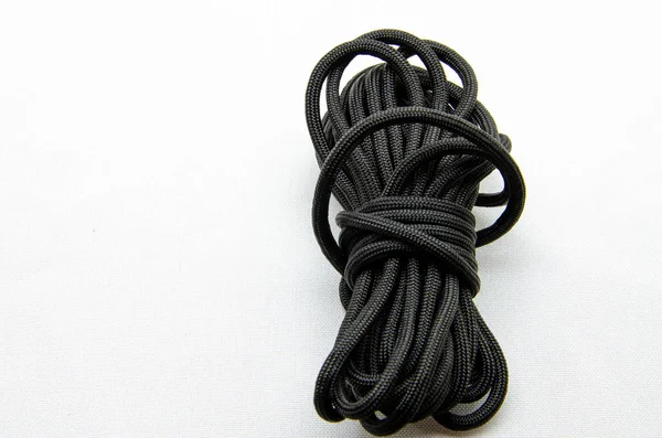İp Paracord. Dokuma ve turizm için paraşüt. Güvenlik halatı. Beyaz arka planda ve ellerinde siyah taktik paraşüt. 