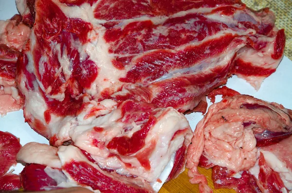 Surowe mięso na desce. Mężczyzna kroi mięso wieprzowe na kawałki nożem. Mięso z bekonem. Choroby surowego mięsa. Tłuste ręce z mięsa — Zdjęcie stockowe