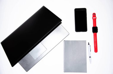 Laptop, akıllı telefon, akıllı saat ve beyaz ve siyah arkaplanlı kalemli defter. Kompozisyon. Farklı yönlerden bak. Kopyala yapıştır, düz kabuk. Çalışmak ve tasarlamak için araçlar. Serbest İşyeri