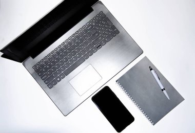 Laptop, akıllı telefon, akıllı saat ve beyaz ve siyah arkaplanlı kalemli defter. Kompozisyon. Farklı yönlerden bak. Kopyala yapıştır, düz kabuk. Çalışmak ve tasarlamak için araçlar. Serbest İşyeri