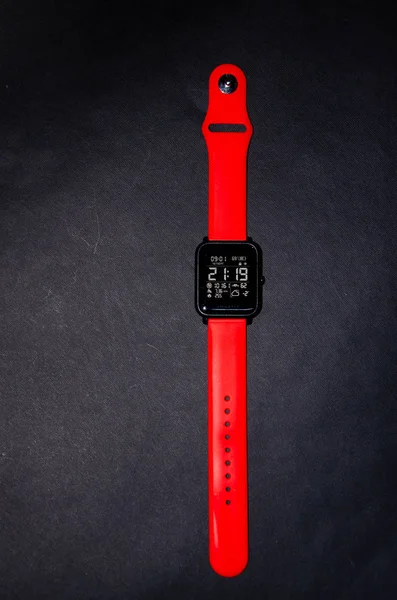 聪明的手表，红色带子。 聪明的手表，手上有明亮的带子，背景是黑色的。 跟踪体育活动。 体育活动 — 图库照片