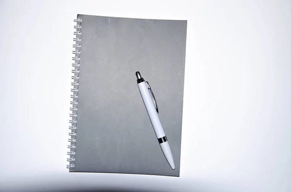 白い背景に白いペンでグレーのノート。ノート、アイデア、タスクのメモ帳。日記 — ストック写真