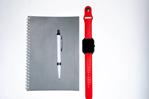 Γκρι σημειωματάριο για γραφή σε μαύρο φόντο. Στυλό. Έξυπνο ρολόι με κόκκινο λουράκι. Flat Lai, αντίγραφα της επικόλλησης. Θέα από διαφορετικές πλευρές. Έξυπνο τηλέφωνο. Επιχειρηματίες που κιτ σύνολο λευκό φόντο. — Φωτογραφία Αρχείου