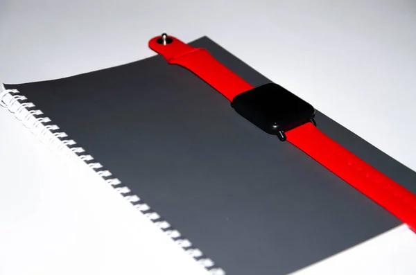 Cuaderno gris para escribir sobre fondo negro. Bolígrafo. Reloj inteligente con correa roja. Flat Lai, copias de la pasta. Vista desde diferentes lados. Smartphone. Juego de hombres de negocios fondo blanco . —  Fotos de Stock