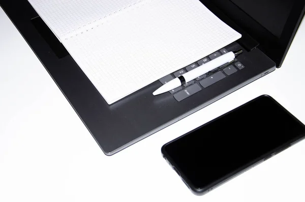 Laptop, smartphone, smart klocka och anteckningsbok med penna på en vit och svart bakgrund. Sammansättning. Utsikt från olika håll. Kopiera pasta, platt bark. Verktyg för det fungerar och design. Frilansare Arbetsplats — Stockfoto