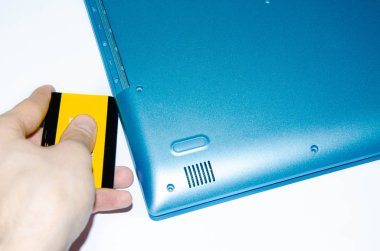 Bir dizüstü bilgisayarı söküyorum. Plastik kartlı bir erkek eli, davanın arka kapağını açar. Sürücü arızalandı. Servis merkezi. Onarım güncellemesi