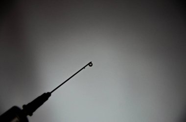 Gri siyah arka planda iğnesi olan bir şırınga. Bir damla, şırıngadan akan bir dere. Makro