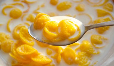 Dilimlenmiş cips şeklinde mısır gevrekleri ve bir tabakta süt. Tabağın üzerinde bir kaşık içinde mısır gevreği. Makro. Arkaplan dokusu. Kahvaltı.