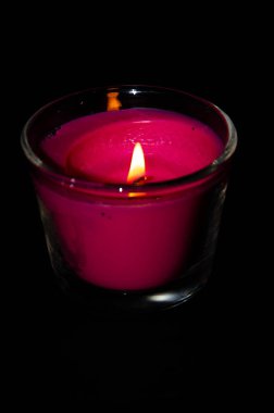 Siyah arka planda cam bir kavanozda parlak pembe bir mum. Mum yanıyordu. Sönmüş mum. Mumdan duman çıkıyor. Ateş çukuru. Alev dili. Makro.