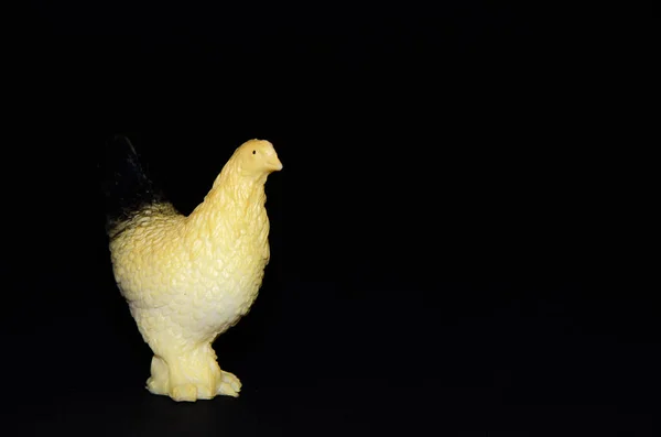 Plastic toy chicken on a black background. Realistic toy  Copy Space