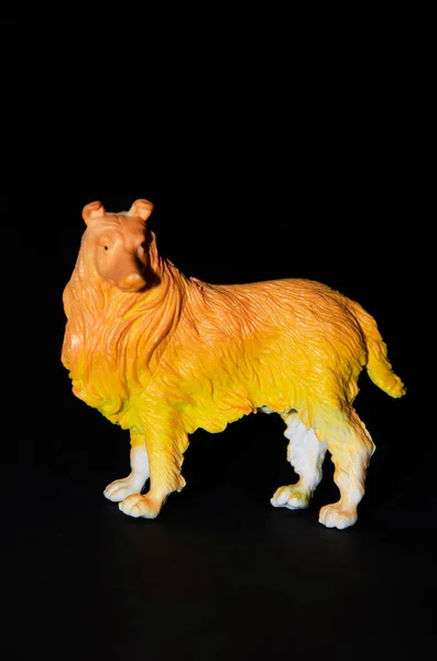 Plastic toy dog on a black background. Realistic toy  Copy Space