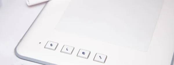 White graphics tablet on a white background. The work of a graphic designer. View of the top, side view. Tablet in macro. Pen stylus for drawing. Buttons on the tablet.