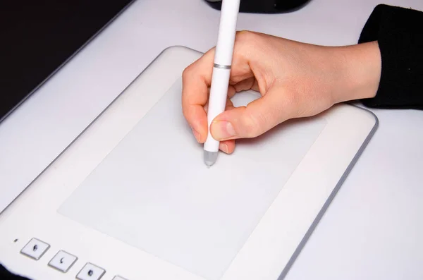 Kadın elleri grafik tablet üzerinde çalışır. El, stil kalemi tutuyor ve çiziyor. Beyaz grafik tablet. Bir grafik tasarımcısının işi. Kız bilgisayara bağlı bir tablet üzerinde çalışıyor. Arkadan görünüm