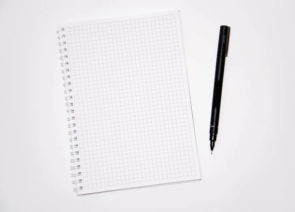 Squared notebook with black pen on a white background. Record ideas, notes, plans, tasks. Notebook top and side view. Flatlay. Copy Space