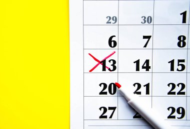 Takvimdeki numaralar sarı arka planda kırmızı haçla işaretlenmiş. Planlar, notlar, toplantılar için takvim. İş takvimi. Takvimdeki notlar için işaretleyici. Ön planda..