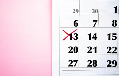 Takvimde kırmızı işaretli bir haç var. Pembe arka planda 13 numara. Takvimde kırmızı kalemle işaretle. Planlar, notlar, toplantılar için takvim. İş takvimi. Spac Kopyala