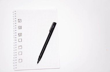 Kontrol listesi. Kare ögeler boş ve bir keneyle kontrol ediliyor. Beyaz arka planda siyah kalemli kare şeklinde bir defter. Fikirleri, notları, planları, görevleri kaydet. Boşluğu Kopyala