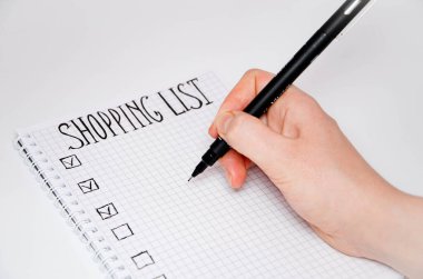 Alışveriş listesi. Elin kalem tutsun. Beyaz arka planda siyah kalemli kare şeklinde bir defter. Fikirleri, notları, planları, görevleri kaydet. Listede ekmek, süt ve muz yer alıyor..