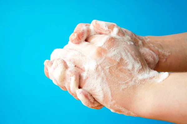 女性の手は石鹸を持っている 手に石鹸泡 手の中に黄色い石鹸 女性は青を背景に両手で石鹸を洗う ウイルス対策 Covid — ストック写真