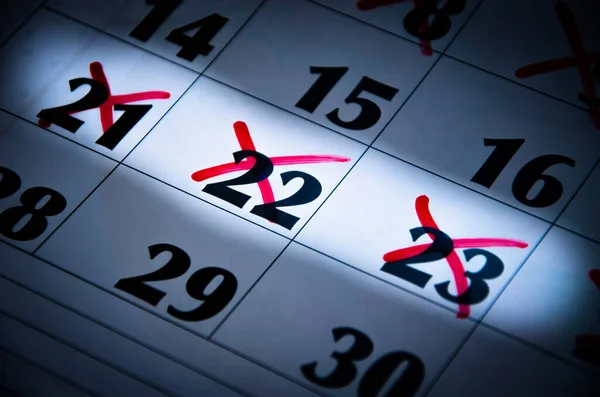 A hand draws a circle on the number 16 on the calendar with a red marker. Crossed out numbers. Highlighted numbers by light. Calendar for plans, notes, meetings. Business calendar.  Copy Space