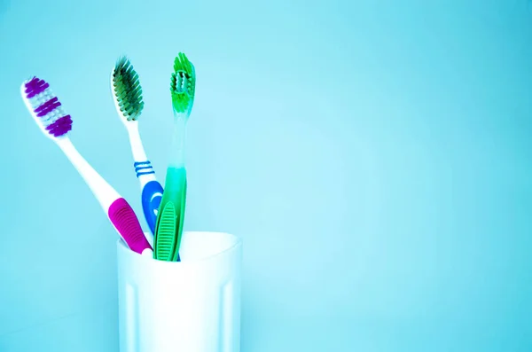 Três Escovas Para Limpar Dentes Vidro Branco Laranja Fundo Azul — Fotografia de Stock